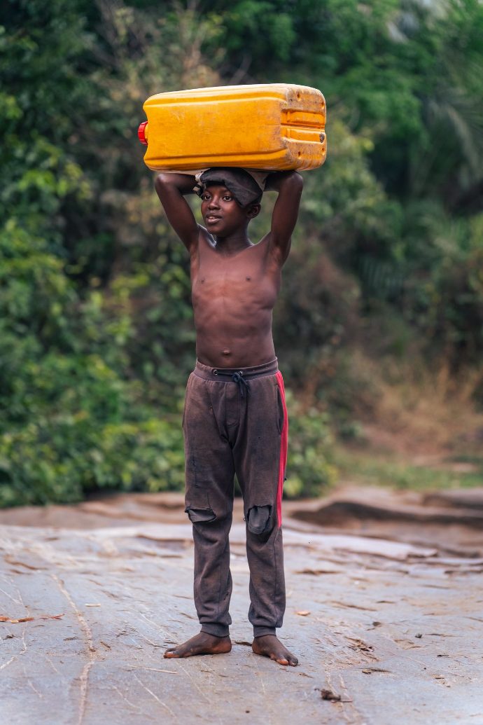 Enfant portant des bidons d'eau